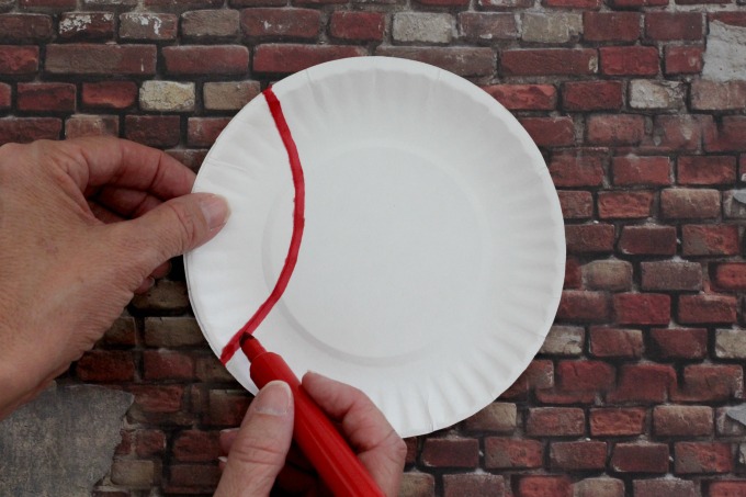 Transform paper plates into baseballs for easy baseball party decor.