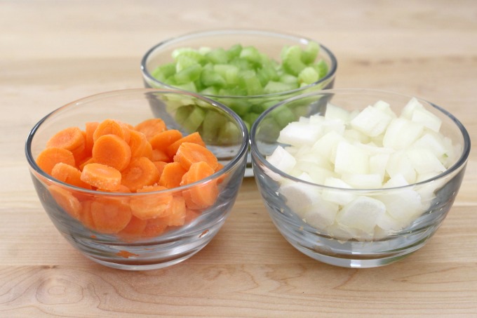 Start your homemade chicken noodle soup by cutting celery, onions and carrots