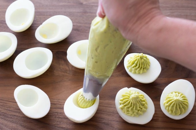 Piping the deviled egg ingredients into the shells