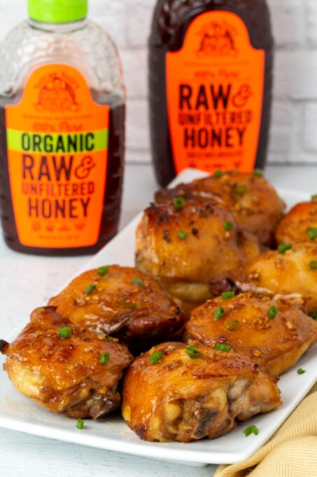 Honey garlic chicken with bottles of Nature Nate's Honey
