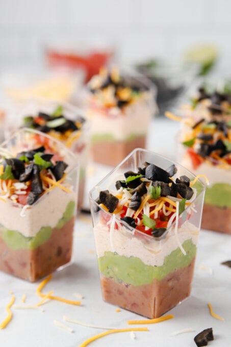 Seven layer dip cups topped with olives and cilantro