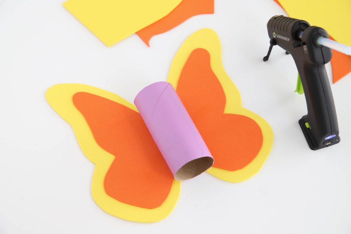 Gluing the pieces for a butterfly toilet paper roll craft