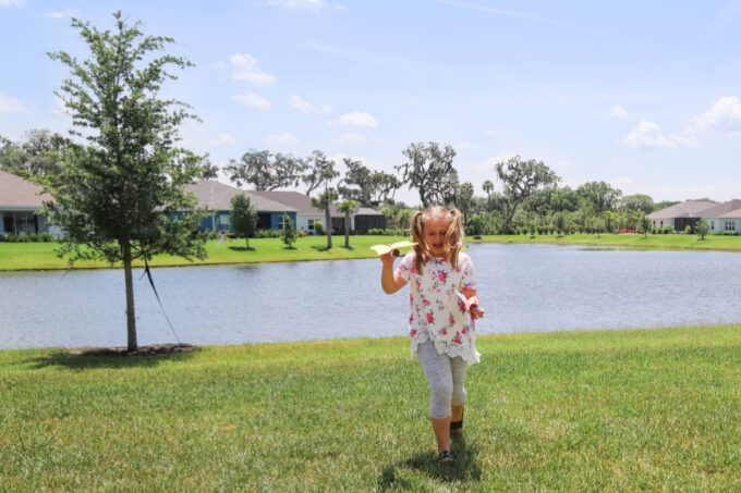 Girl playing with toilet paper roll butterfly in yard