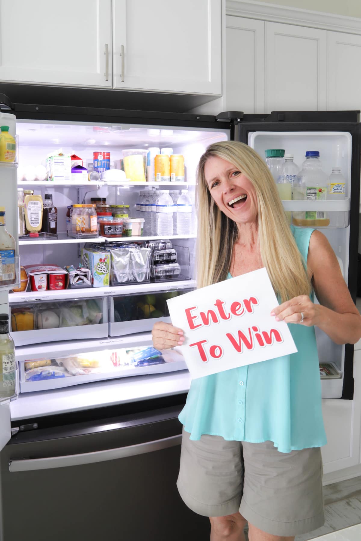 Woman holding enter to win sign in front of fridge