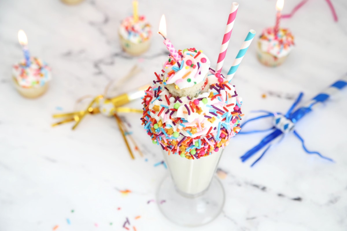 Birthday cake milkshake with sprinkles and a cupcake