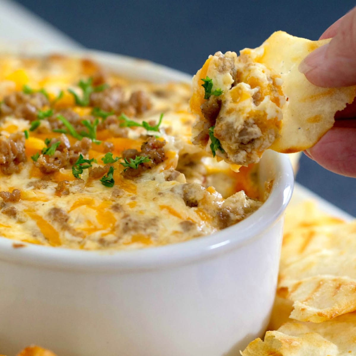 Hand dipping a chip into cheese dip