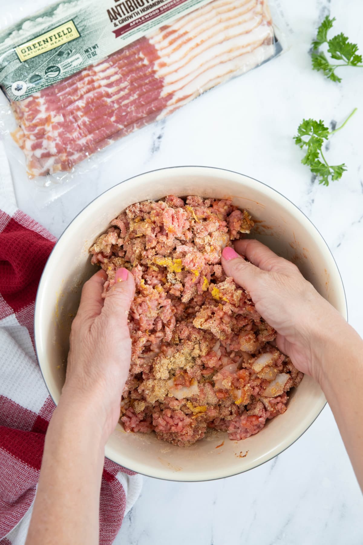Using hands to blend meatloaf ingredients