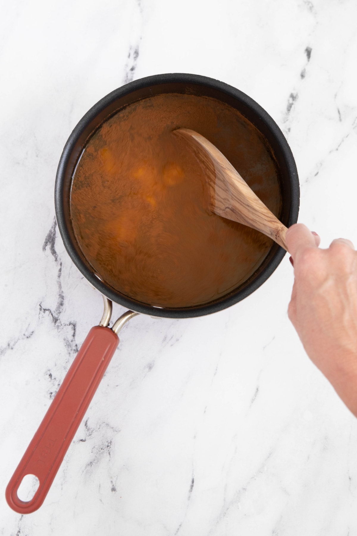 Stirring ingredients for pumpkin juice in saucepan