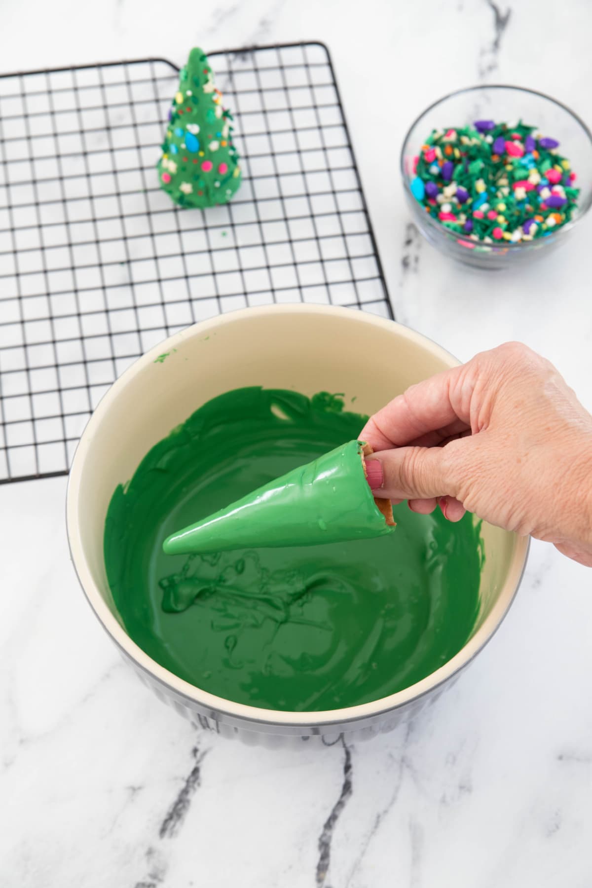 Dipping an ice cream cone in green candy melts