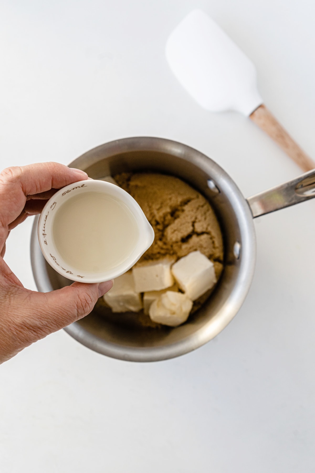 Brown sugar and butter in a mixing bowl with cup of cream