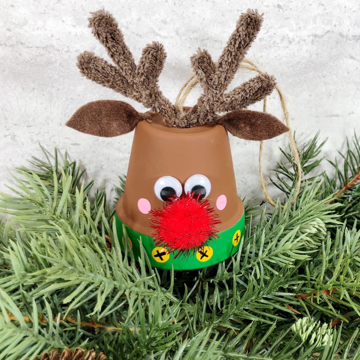 Clay pot reindeer ornament on pine branch