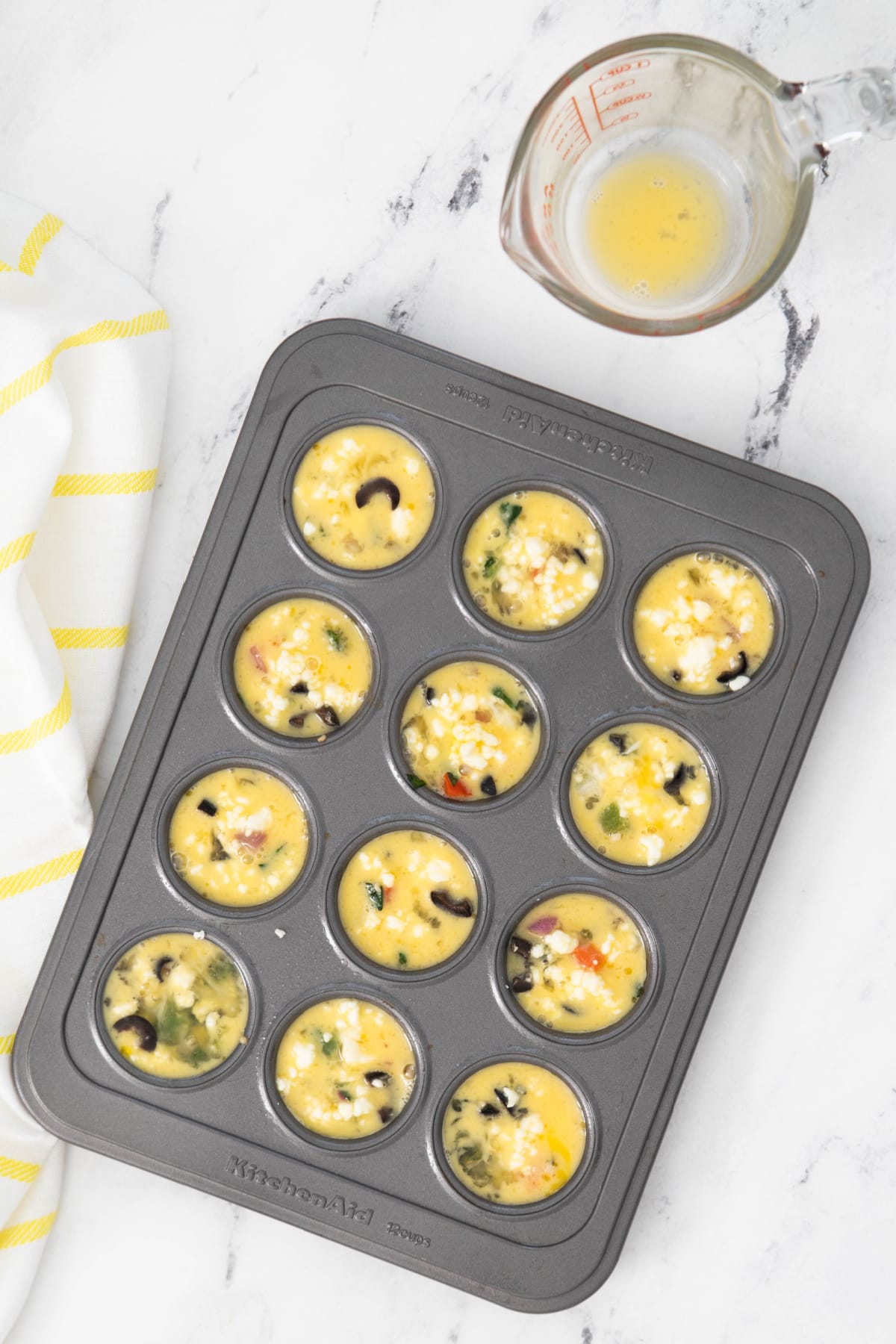 Eggs added to veggies in mini muffin pan