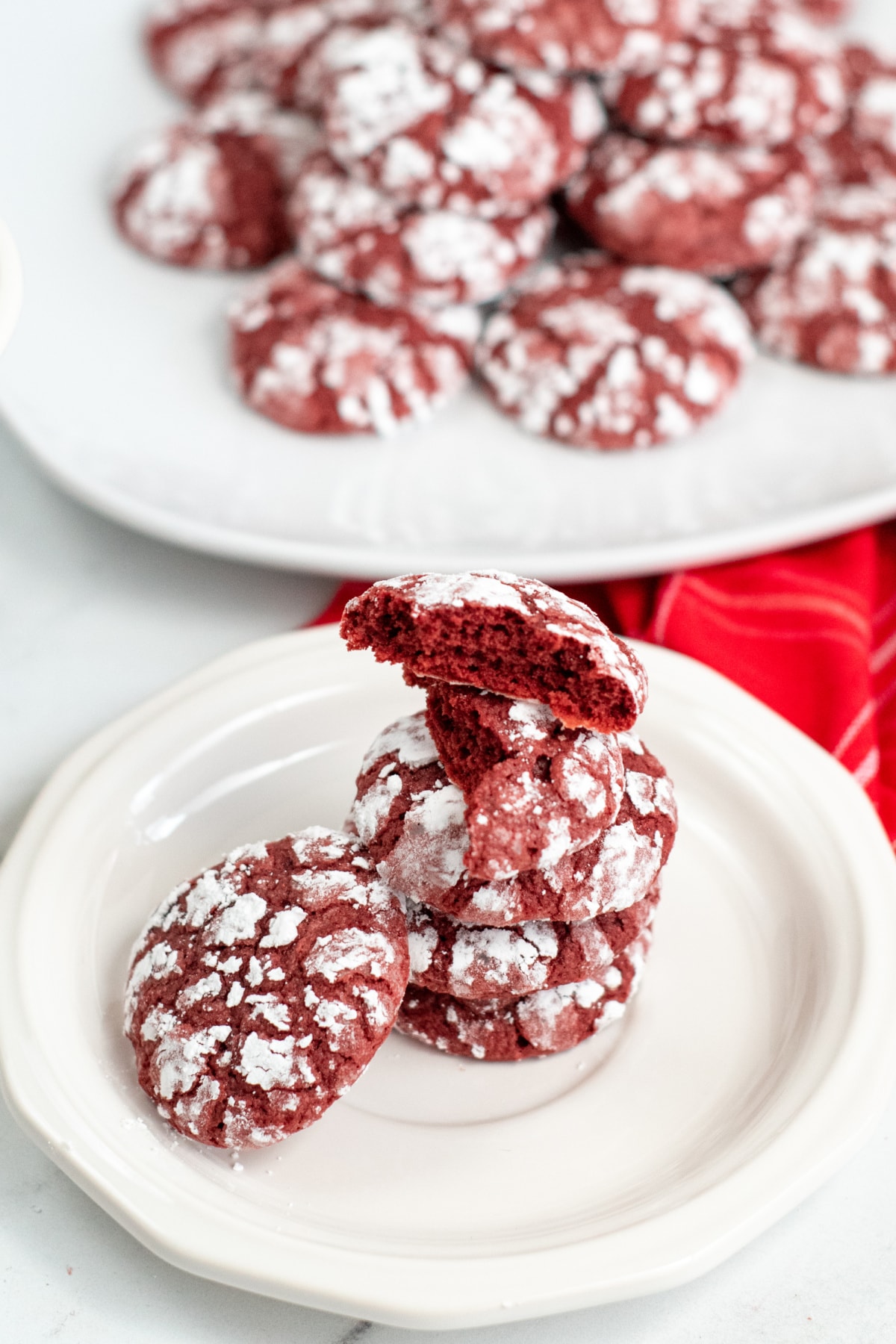 Red velvet crinkle cookies stacked on white plate