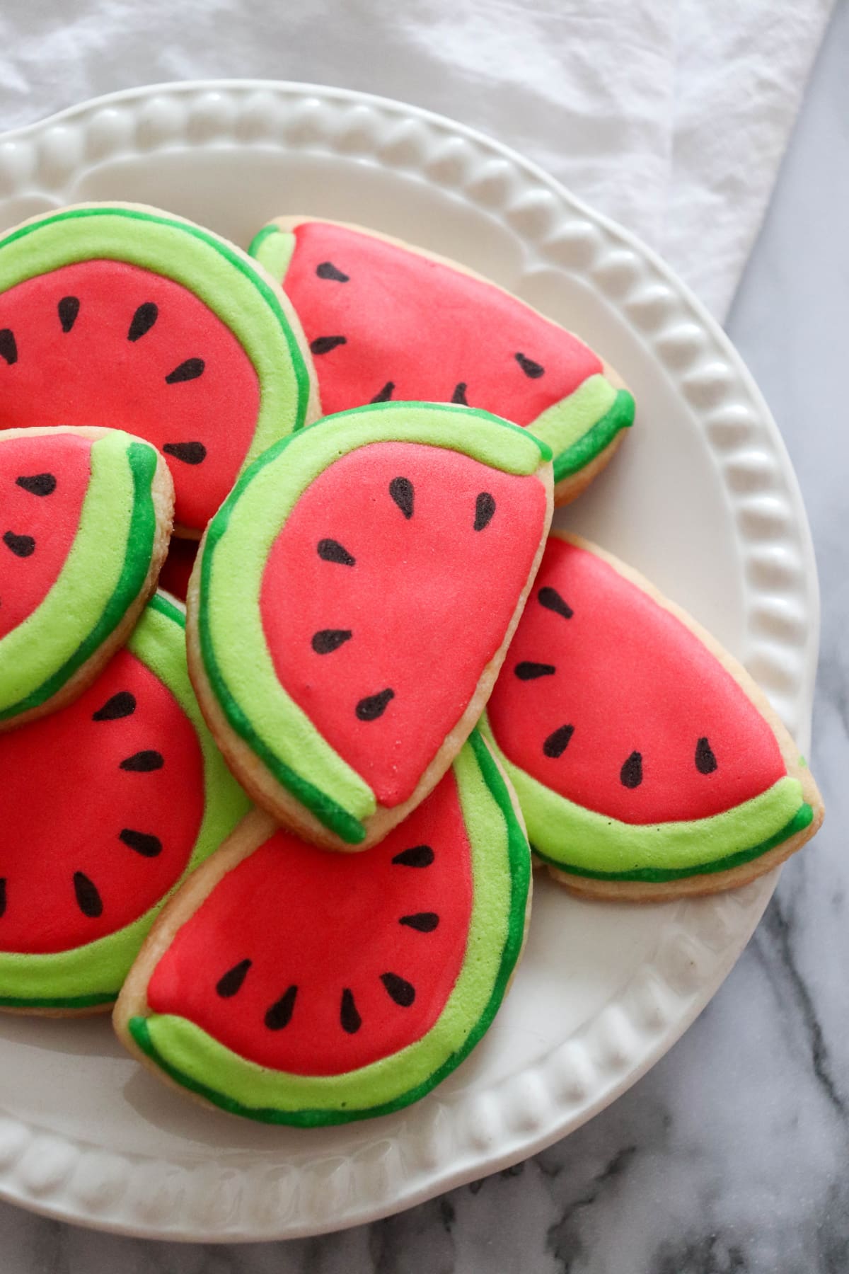 Watermelon cookies stacked on white plate