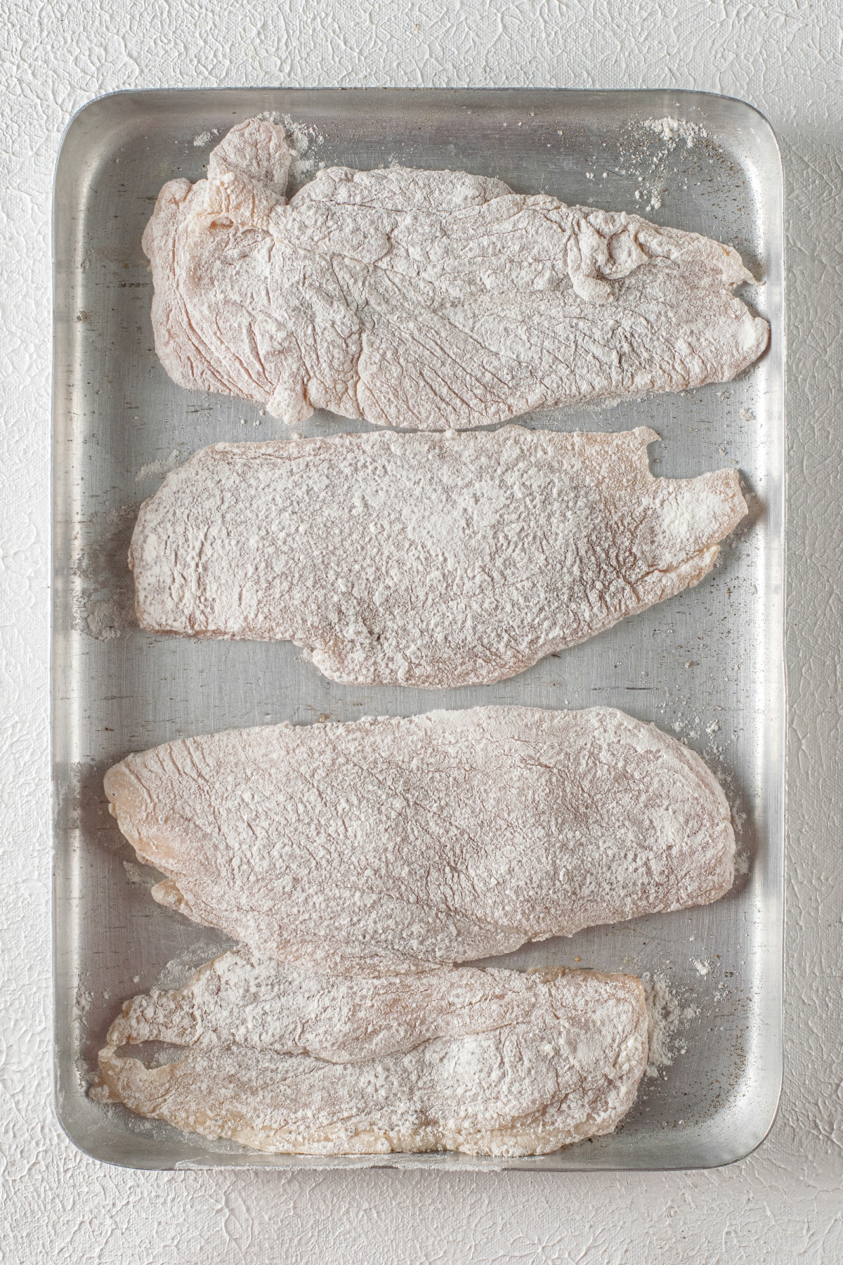 Chicken breasts coated in flour for chicken piccata recipe