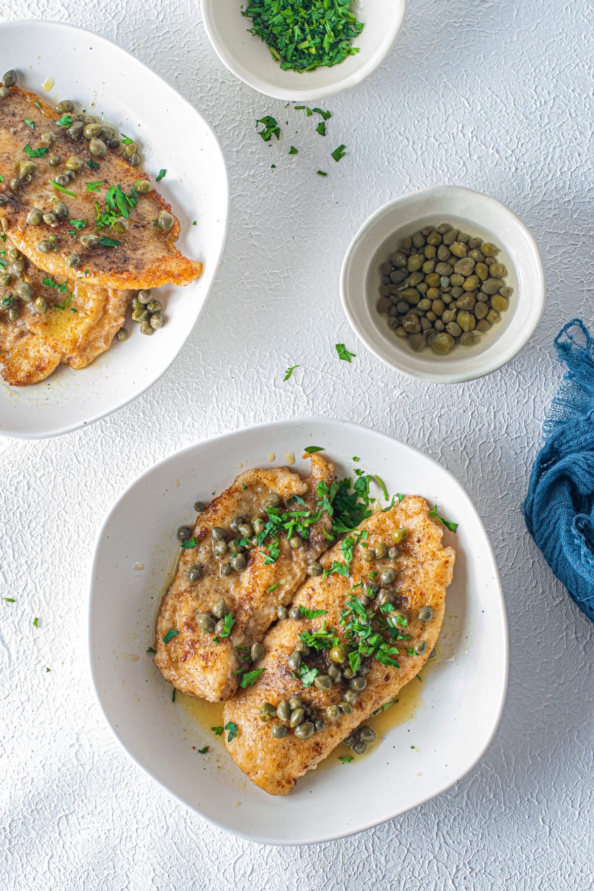 Chicken piccata with parsley in white dish
