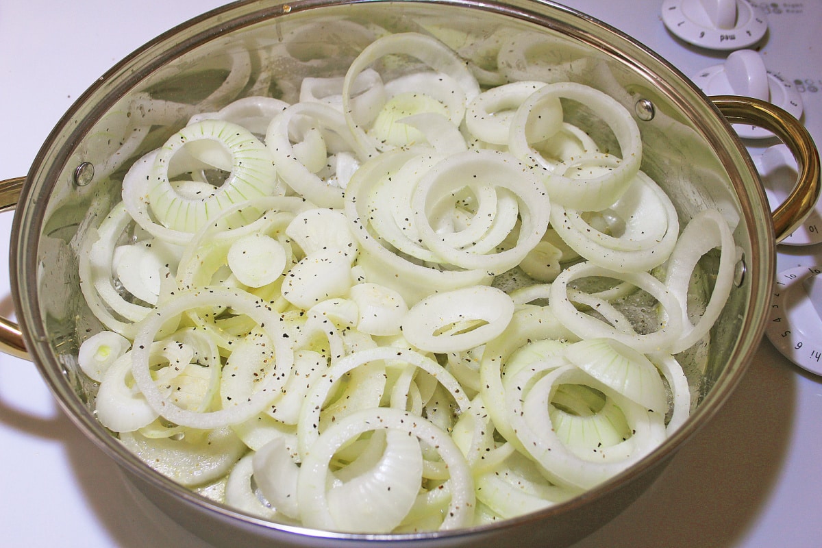 Uncooked onion rings in pan with seasonings