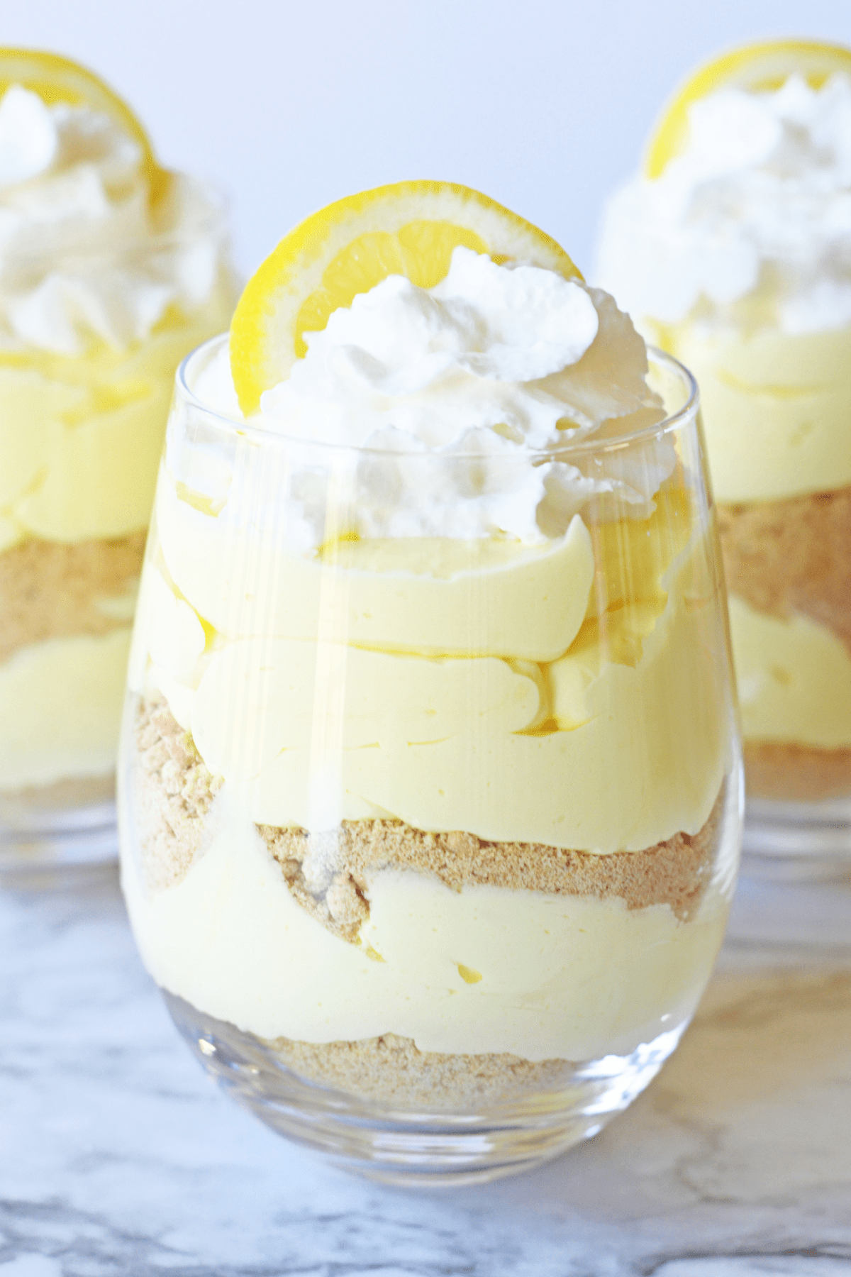 Lemon Cheesecake Parfait topped with whipped cream and lemon