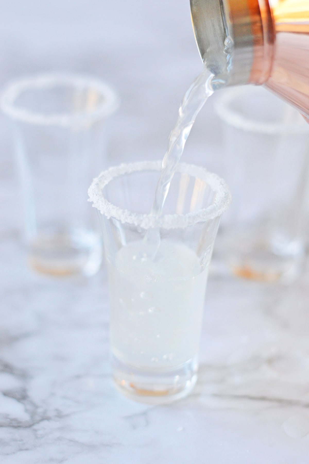 Pouring lemon drop shots into glasses