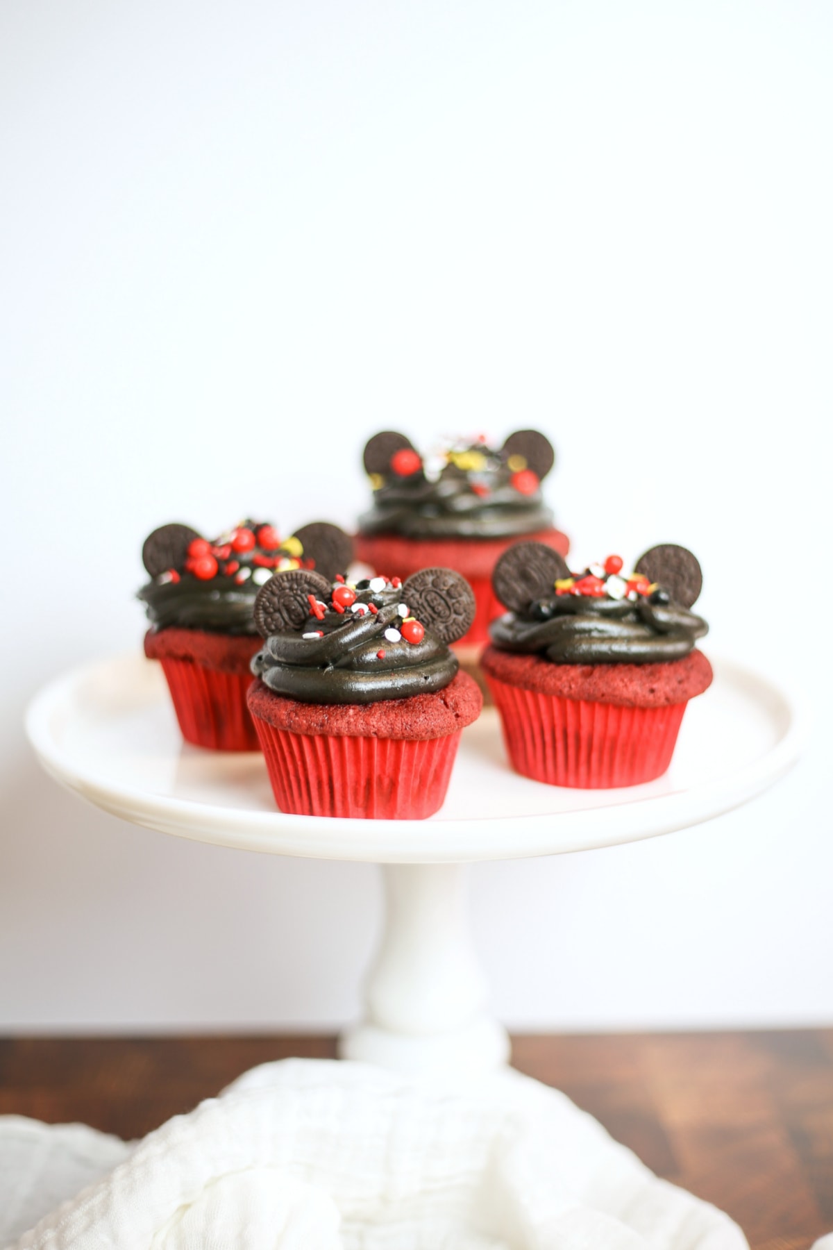 Four Mickey Mouse cupcakes on white cake plate
