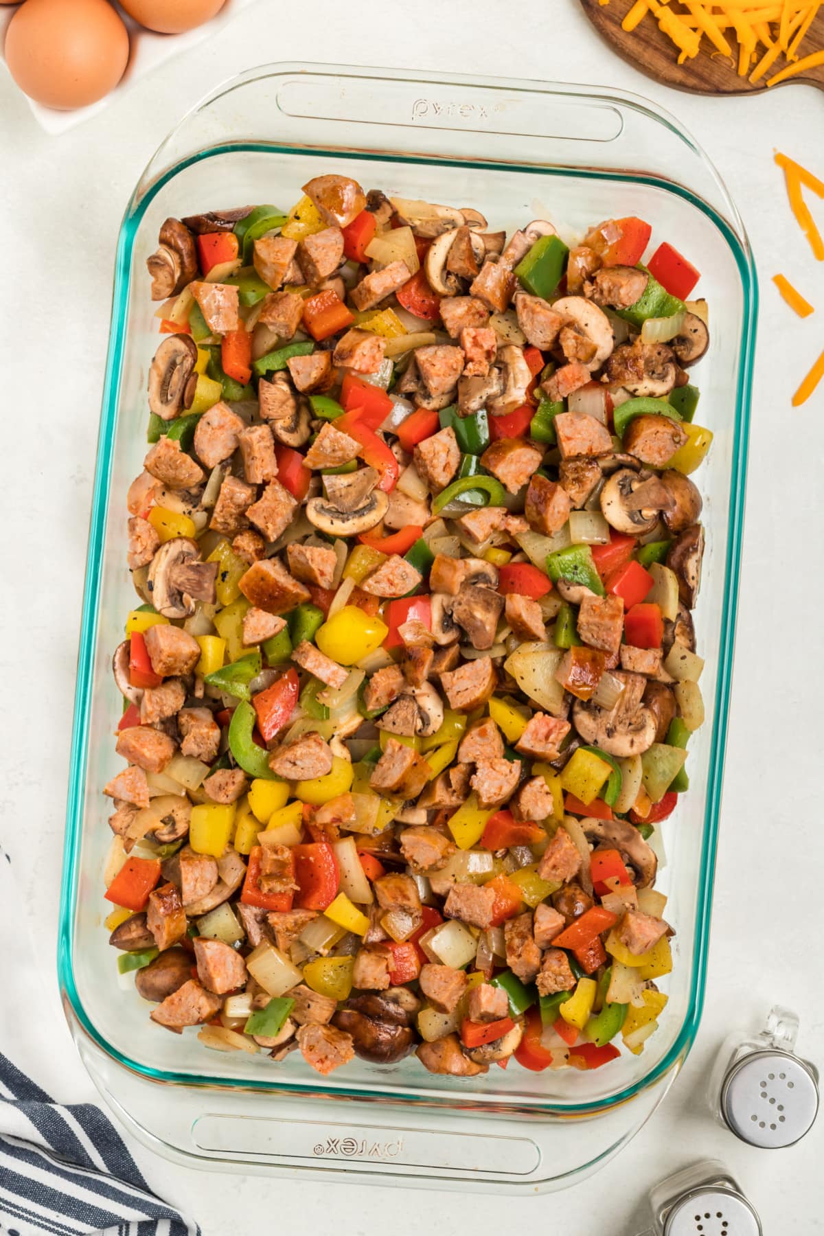 Veggies with sausage and cheese in glass baking dish