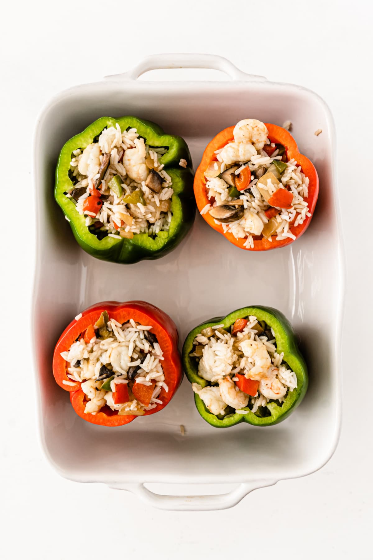 Four stuffed peppers in white baking dish