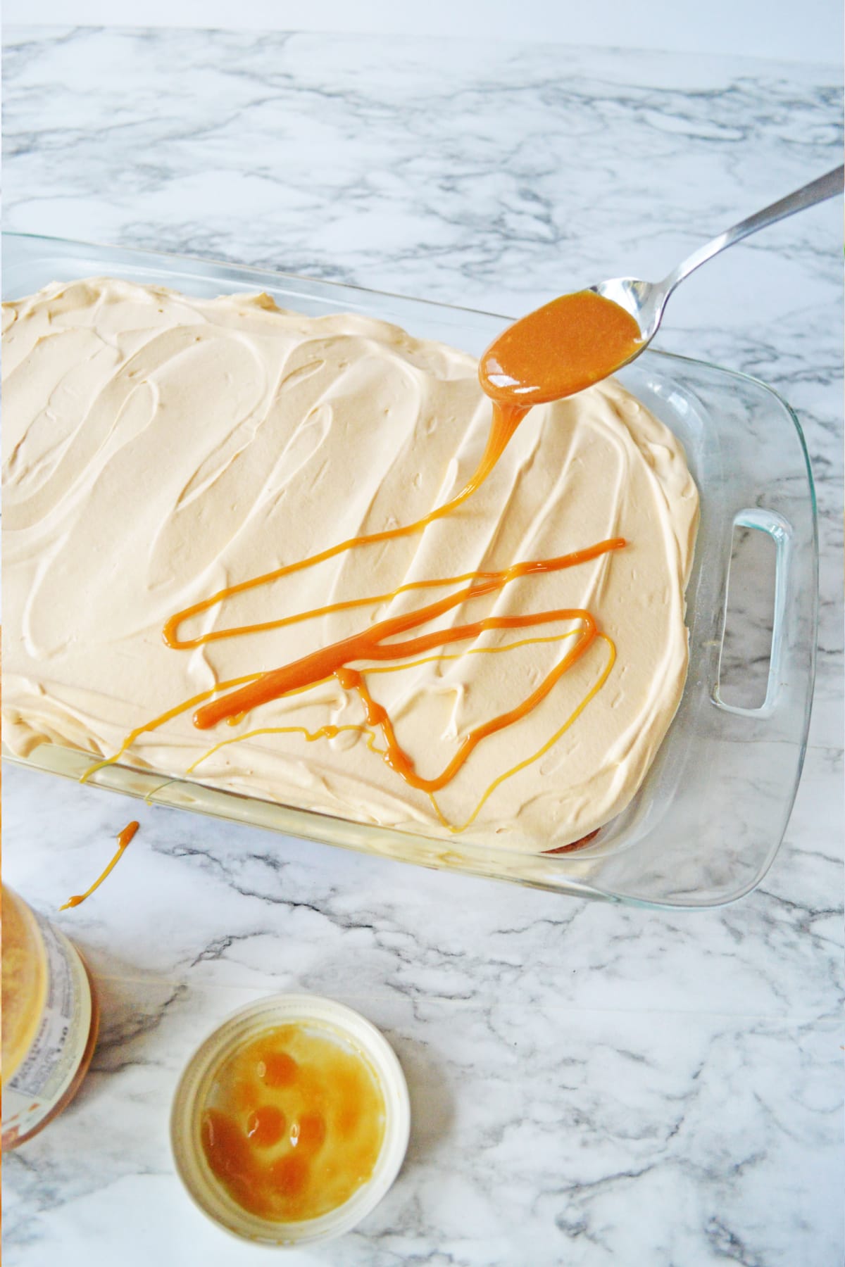 Butterscotch syrup being drizzled over poke cake
