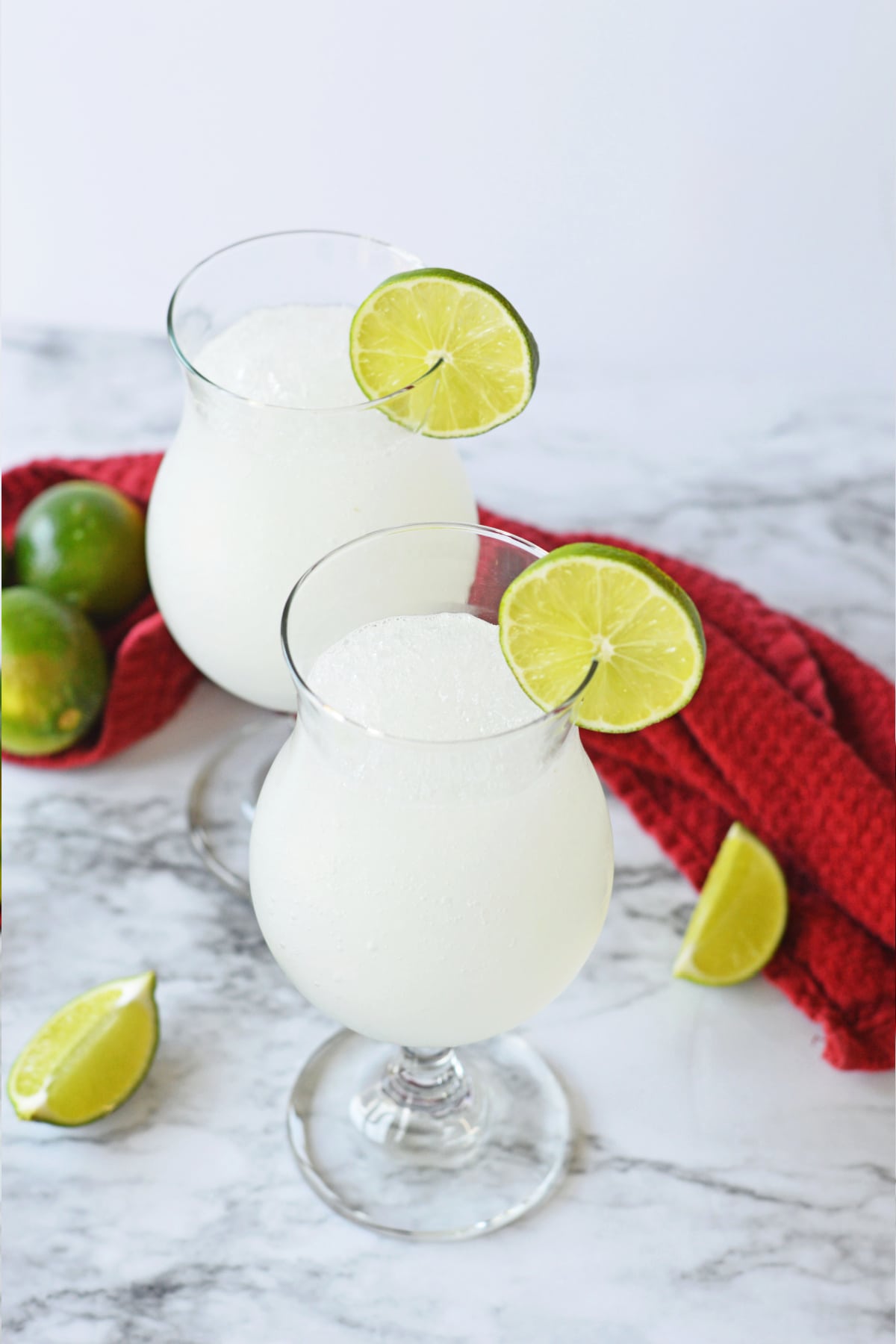 Two frozen daiquiris with red towel and limes