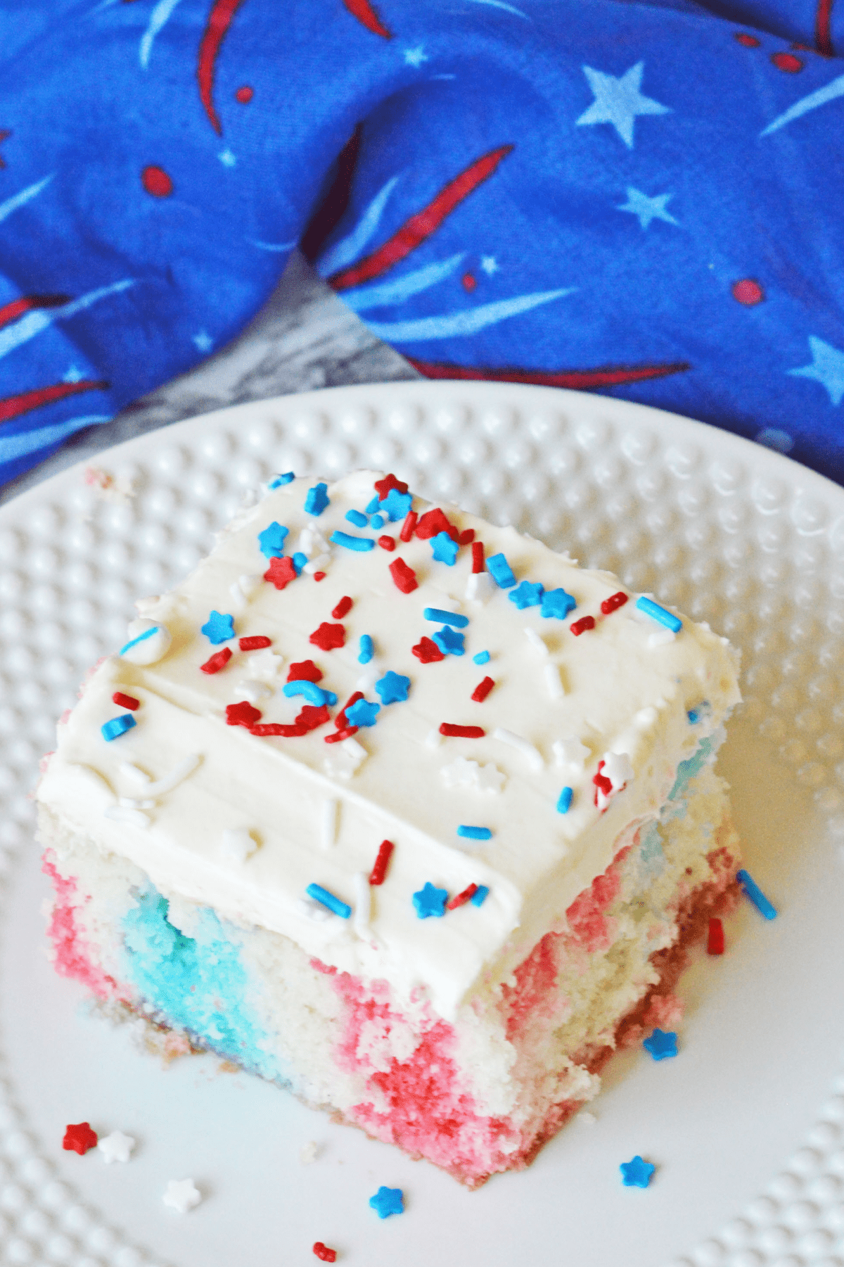 Red White And Blue Poke Cake on white plate with blue napkin