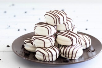 White chocolate covered Oreo cookies stacked on brown plate