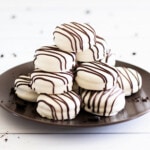 White chocolate covered Oreo cookies stacked on brown plate