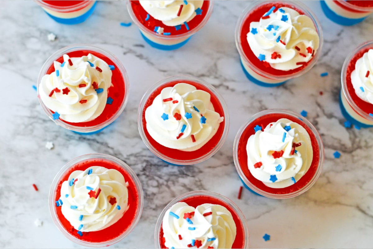 Red white and blue sprinkles on top of whipped cream & jello shots
