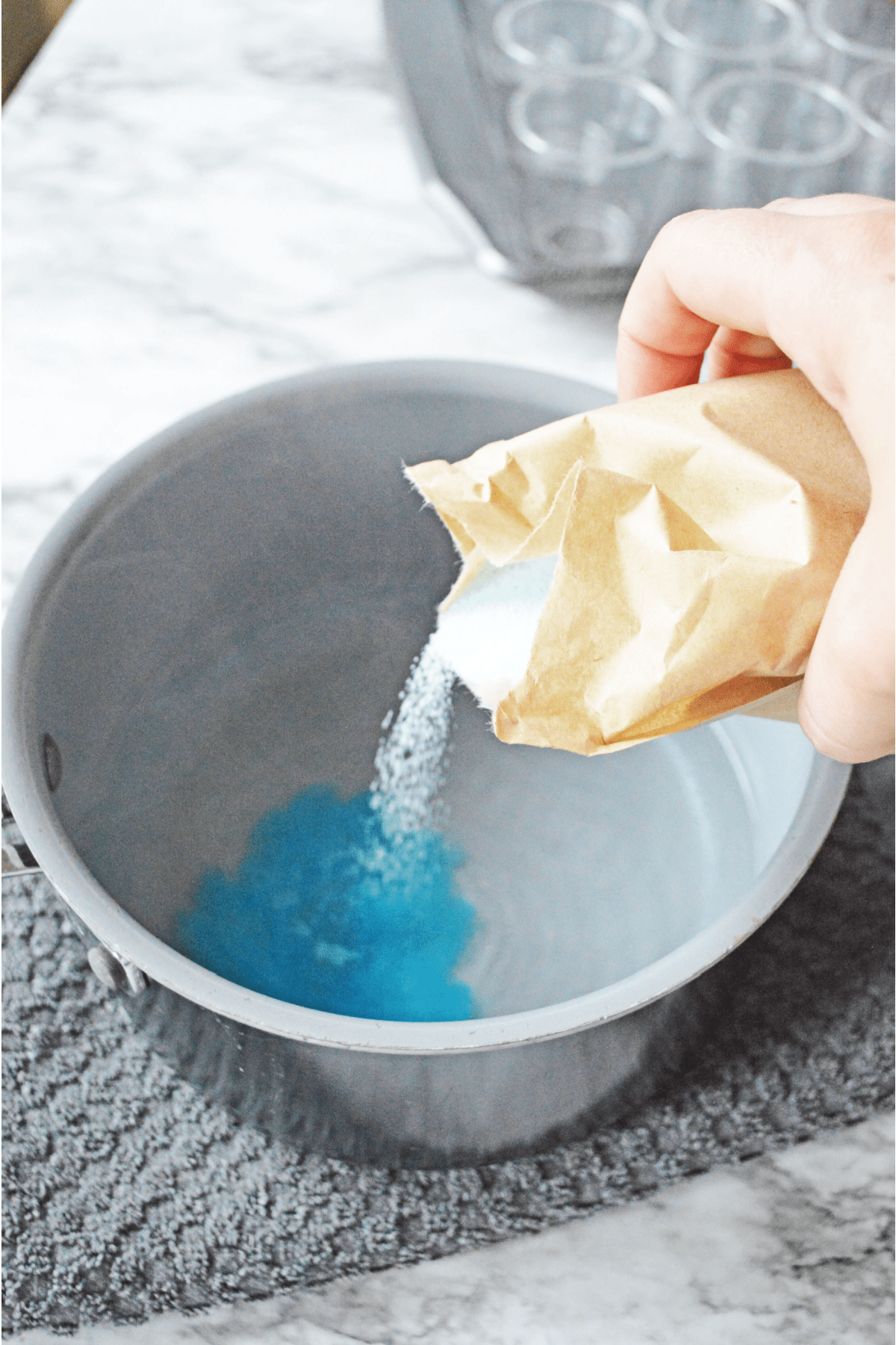 Pouring blue jello packet into pot of hot water
