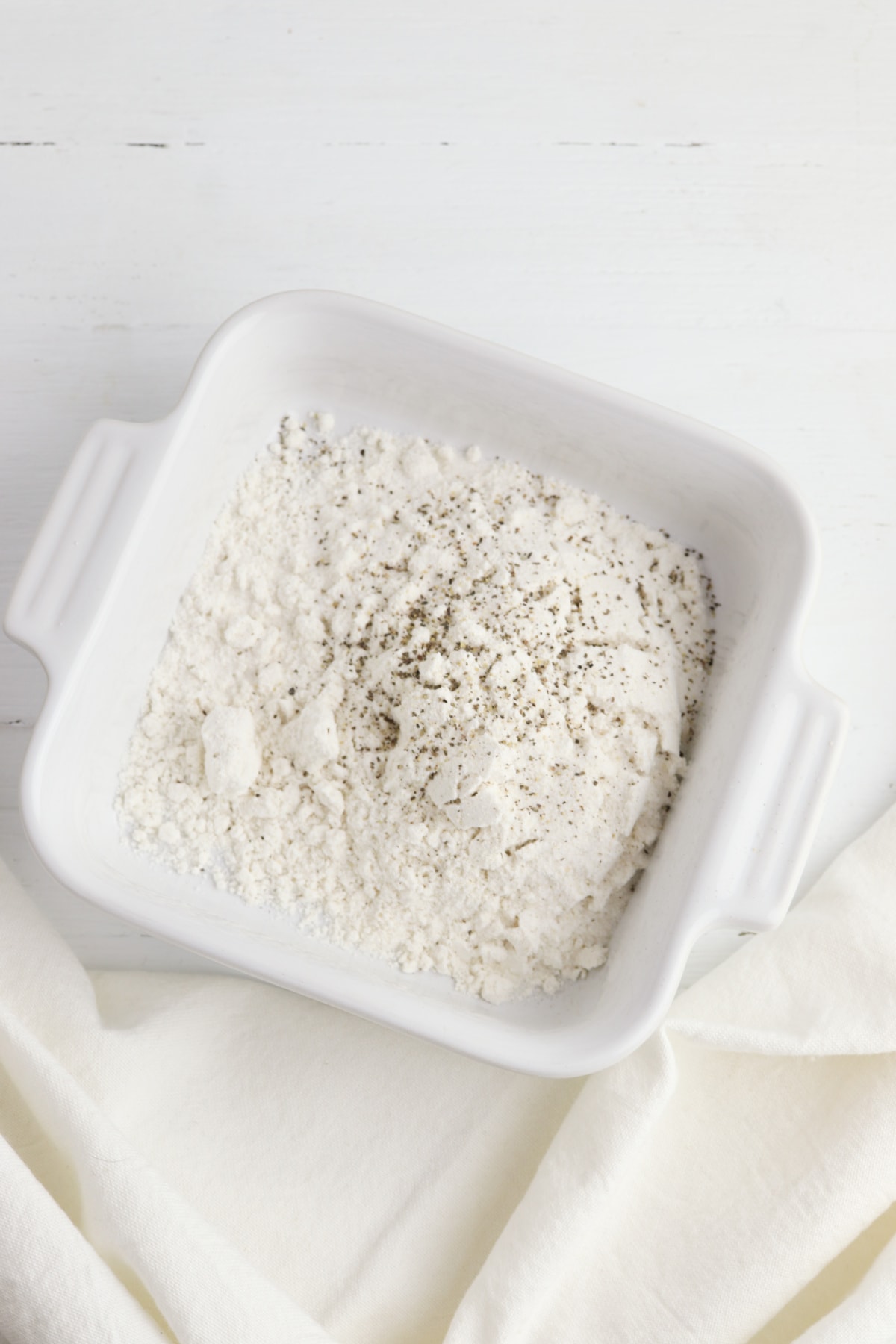 Flour with salt and pepper in white bowl