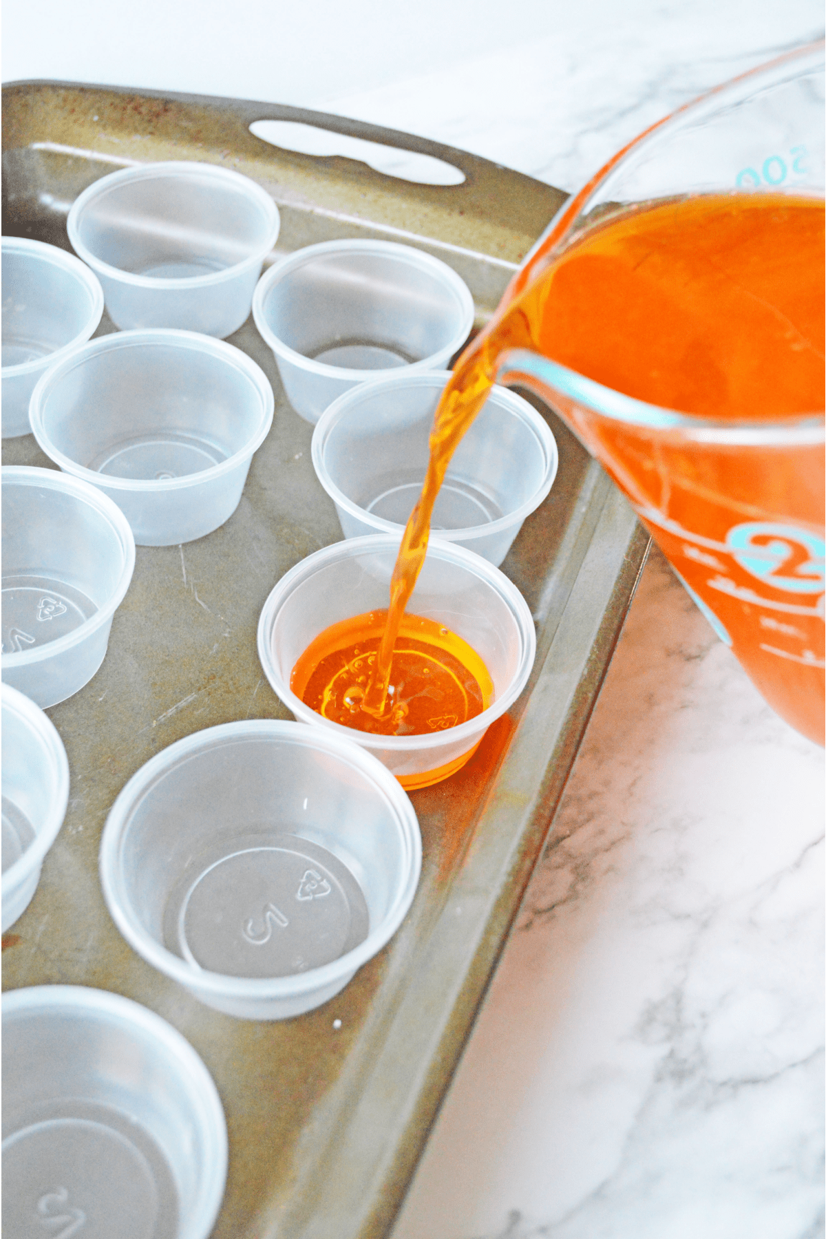 Pouring liquid for Jello shots into plastic cups