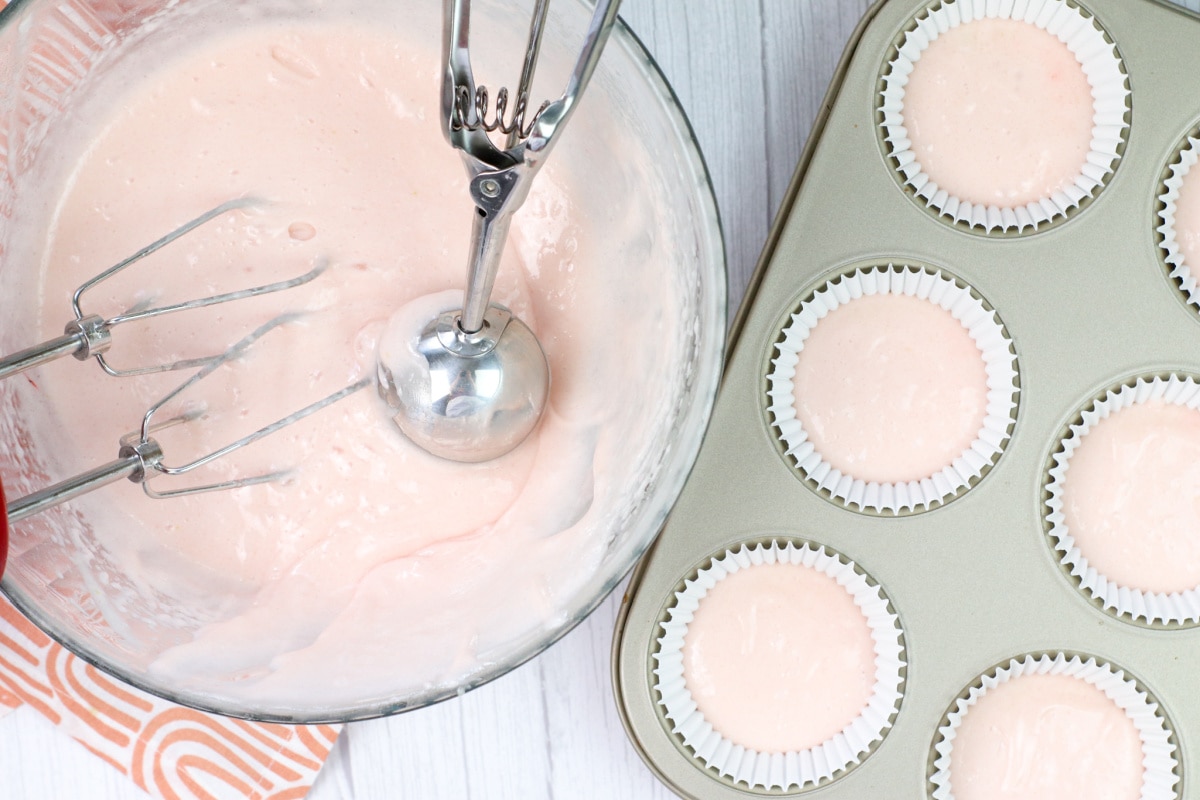 Scooping cupcake batter into tins