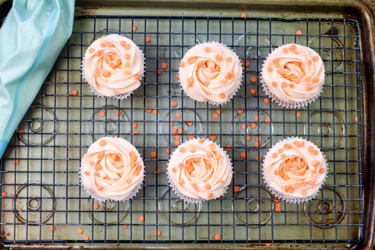 Cupcakes topped with peach icing and sprinkles