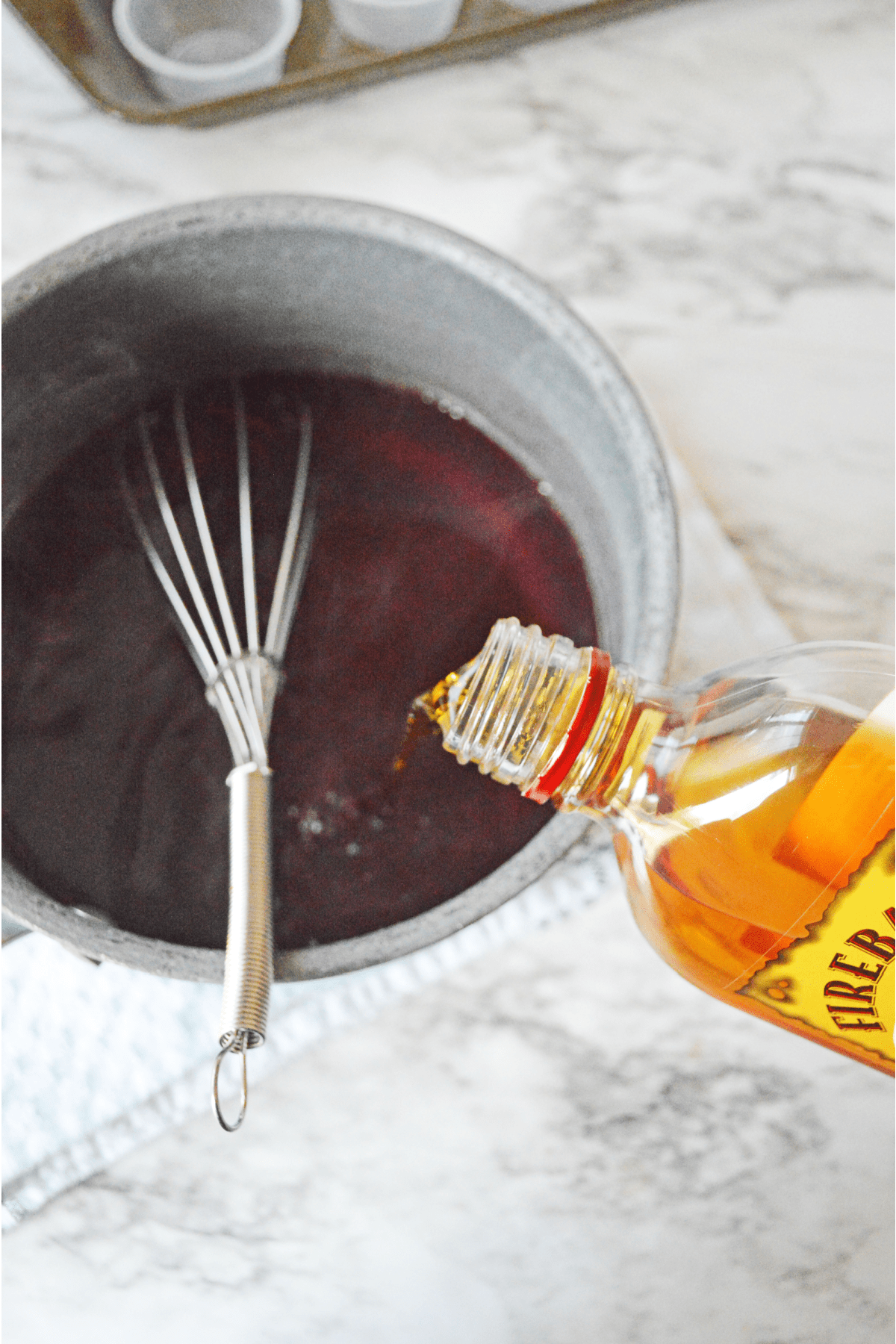 Pouring fireball cinnamon whiskey into cherry jello mixture