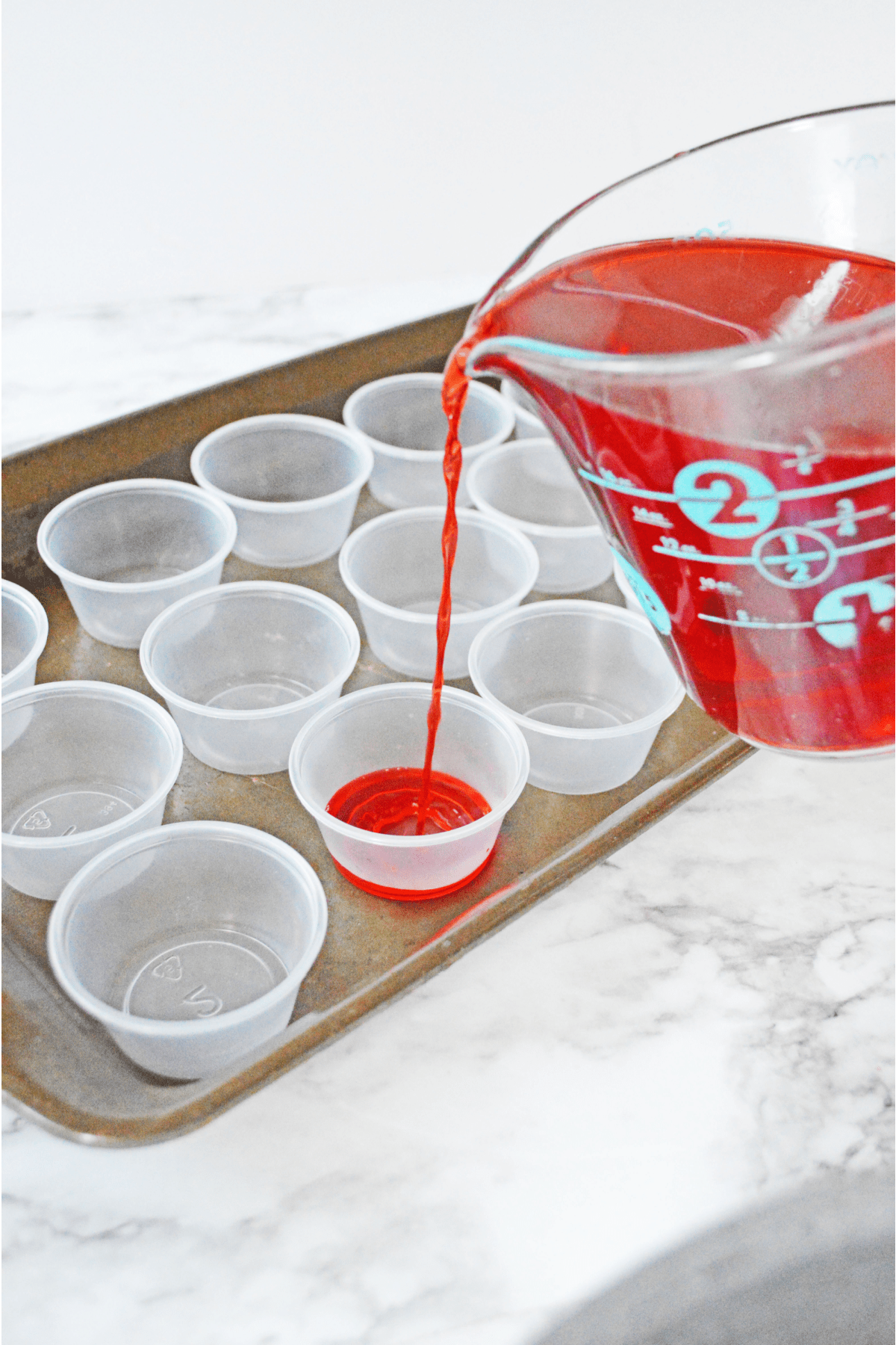 Pouring jello shot mixture into plastic shot cups
