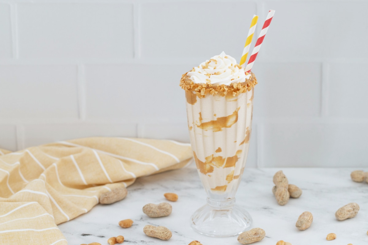 Peanut butter milkshake with peanuts and tan dish towel