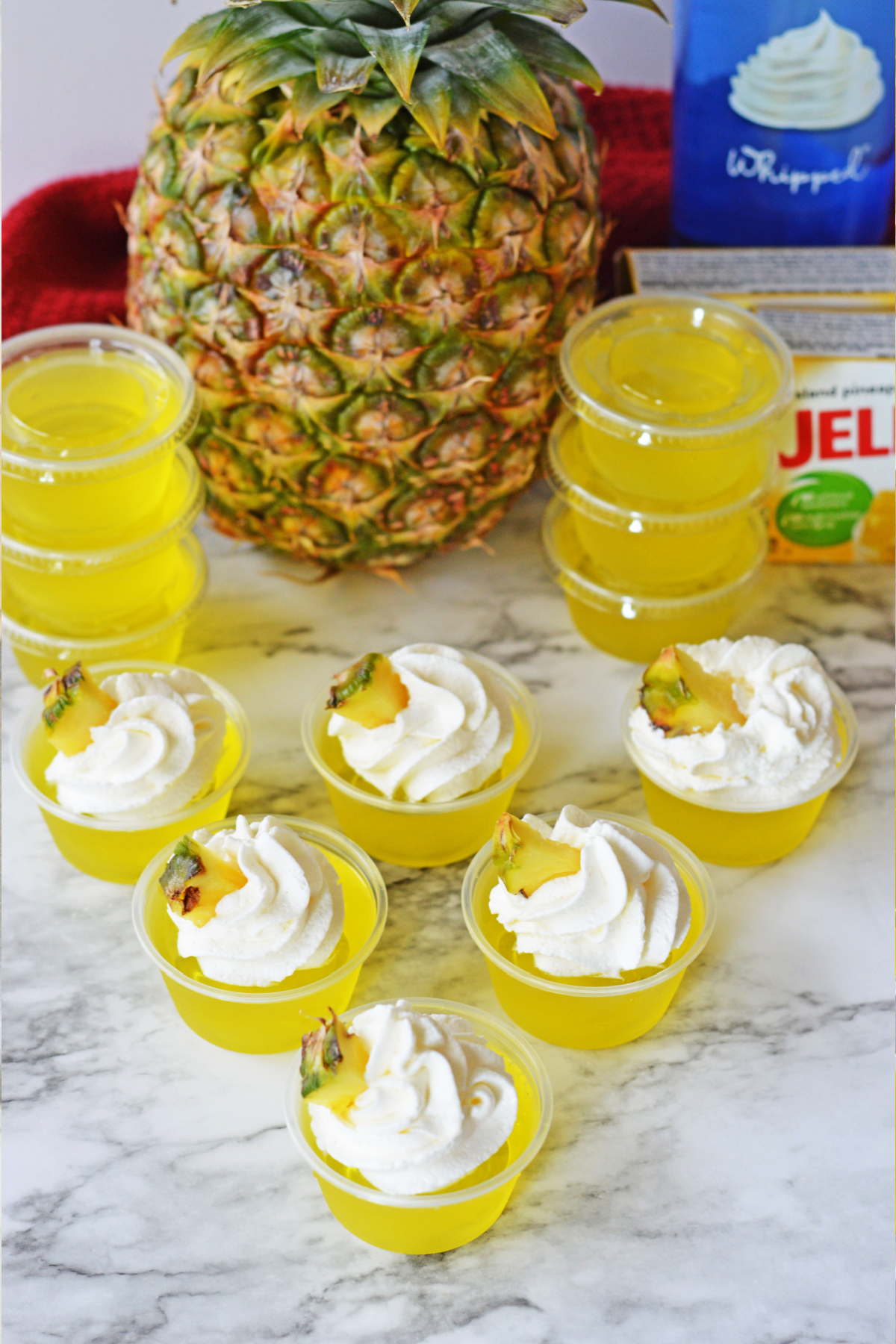 Pineapple jello shots with fresh pineapple in background