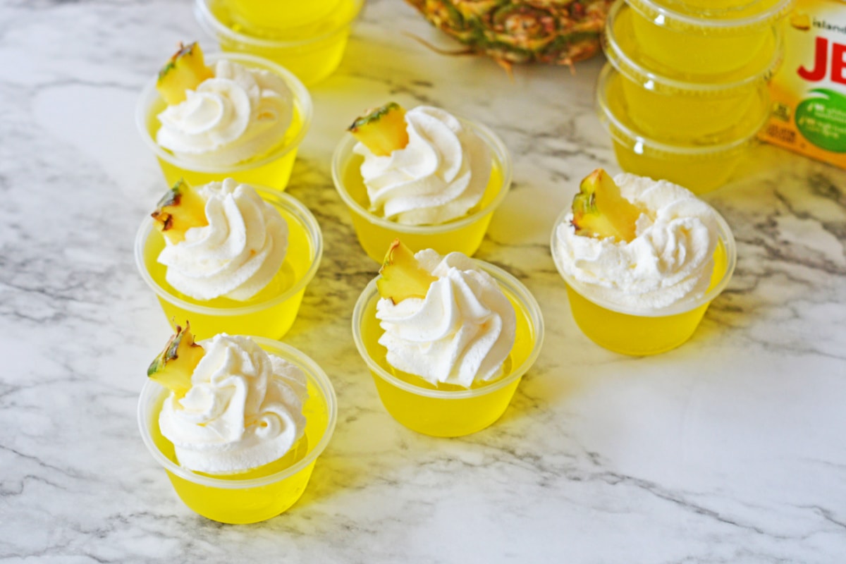 Pineapple jello shots topped with whipped cream and pineapple