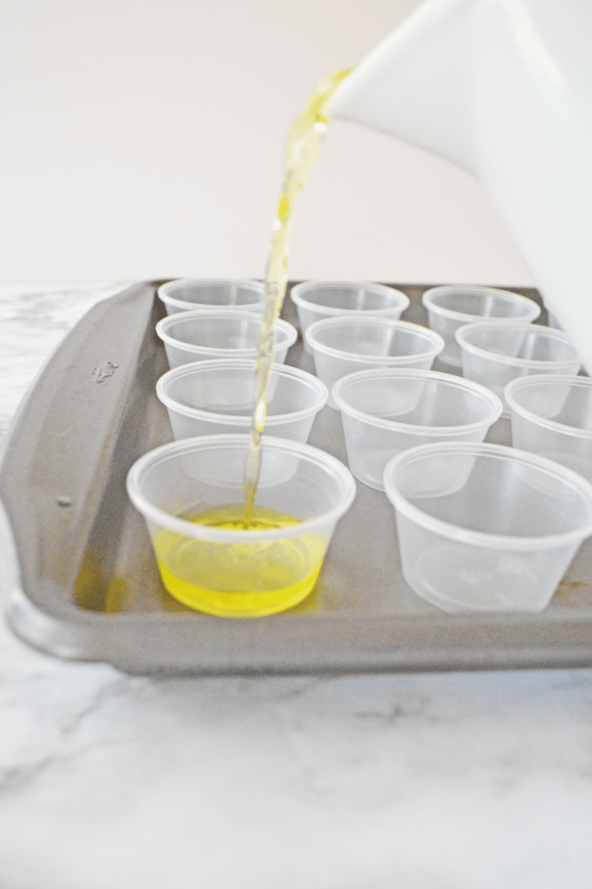 Pouring jello shot mixture into plastic cups