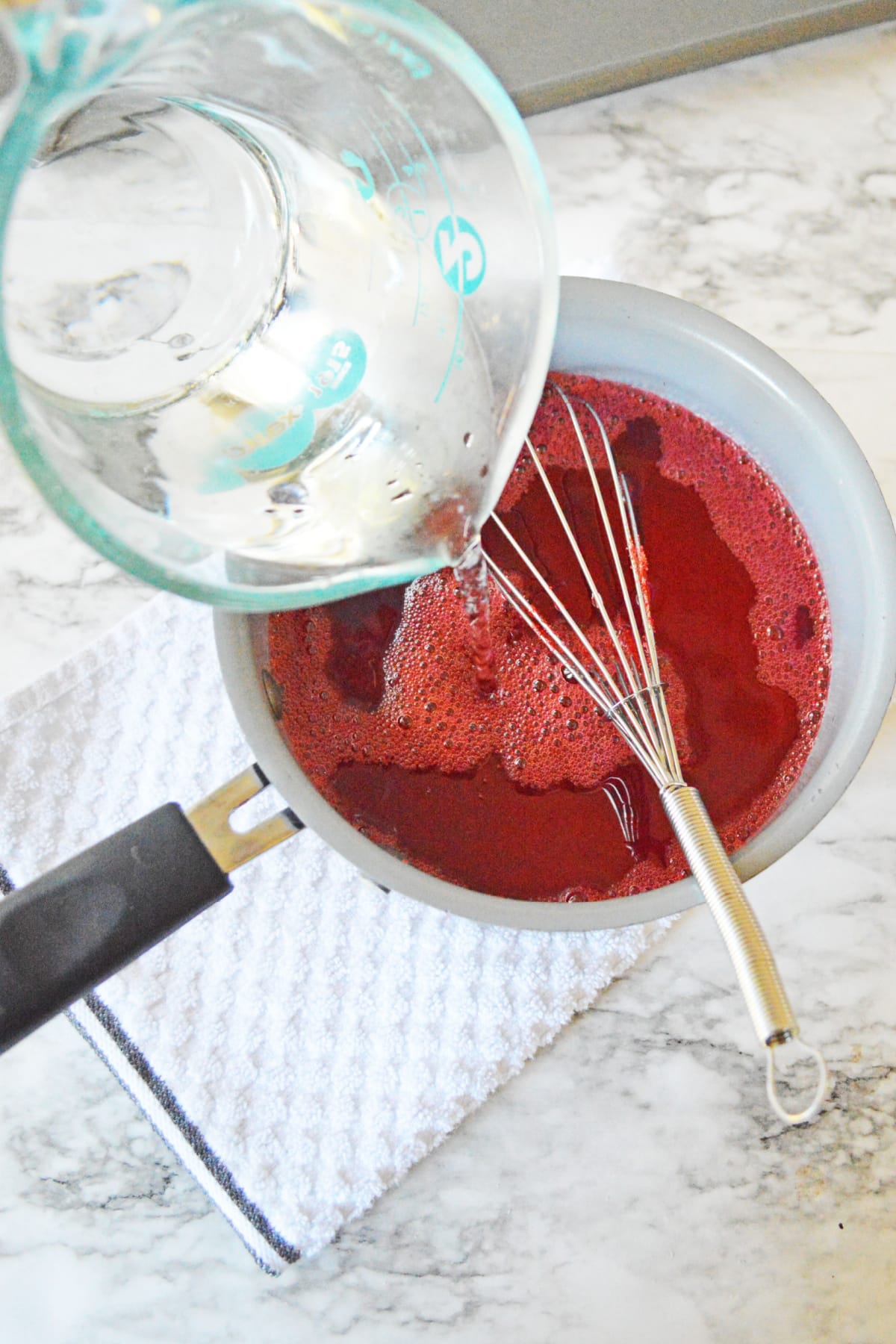 Pouring water into saucepan with jello