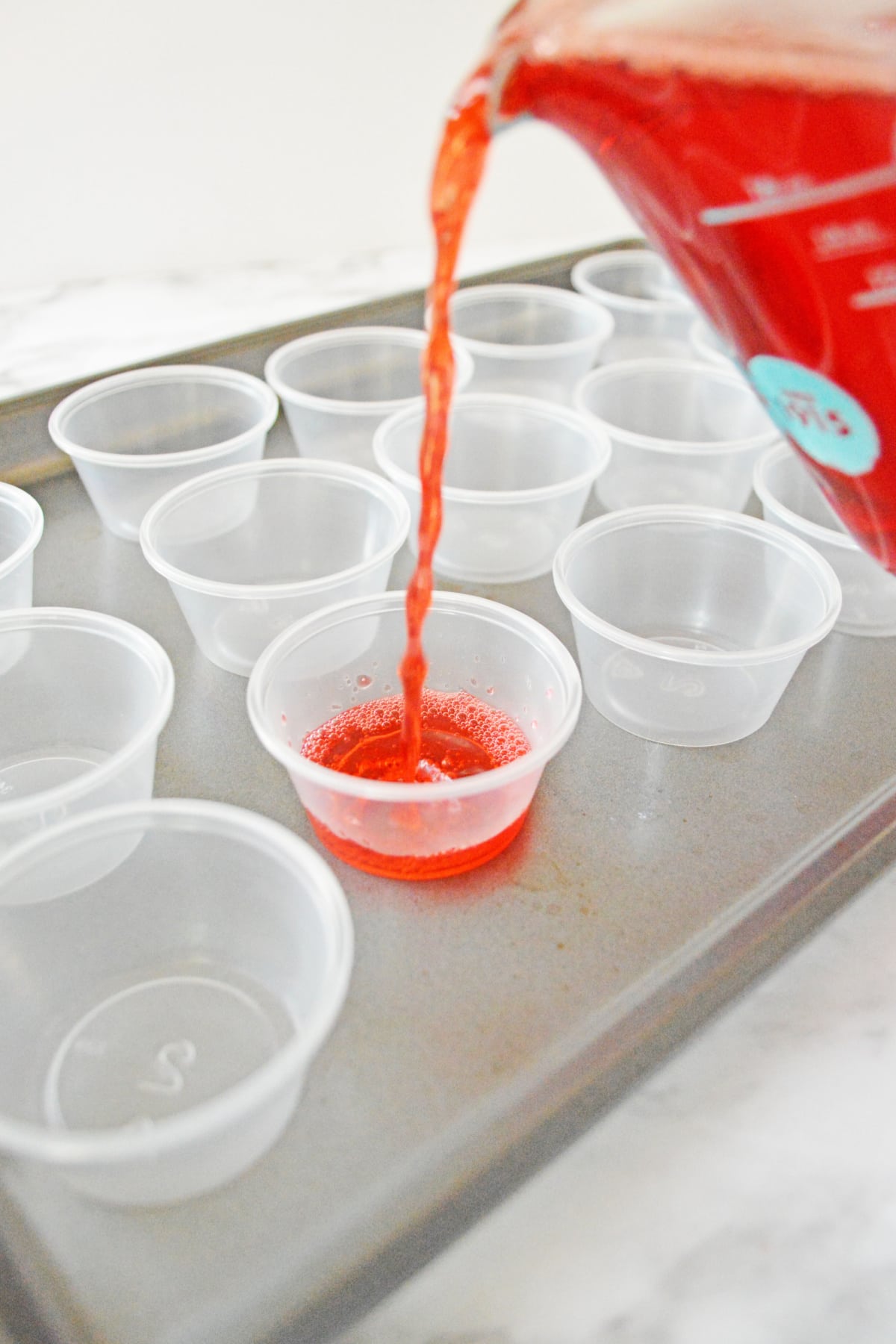 Pouring Jello vodka shot mixture into plastic cups