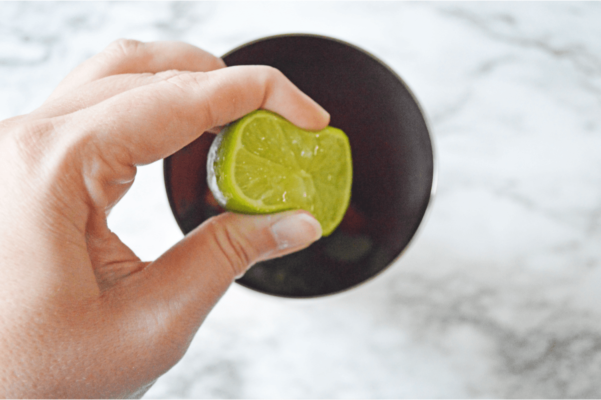 Lime being squeezed into cocktail shaker