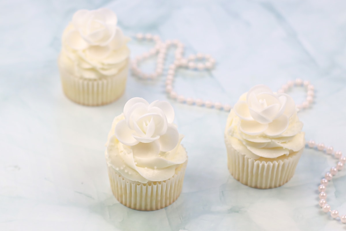 Three white cupcakes on marble counter