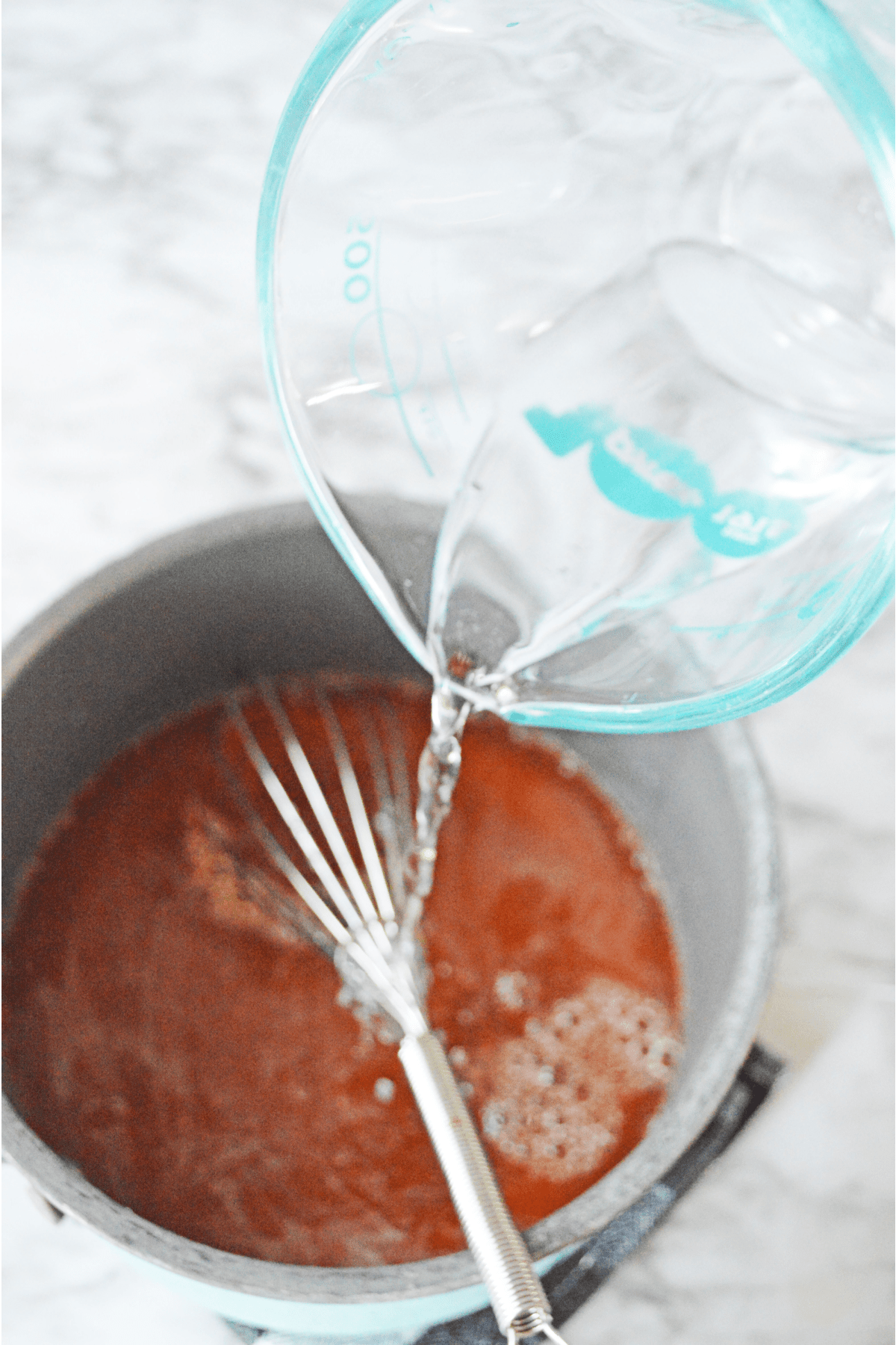 Pouring water into saucepan with orange jello