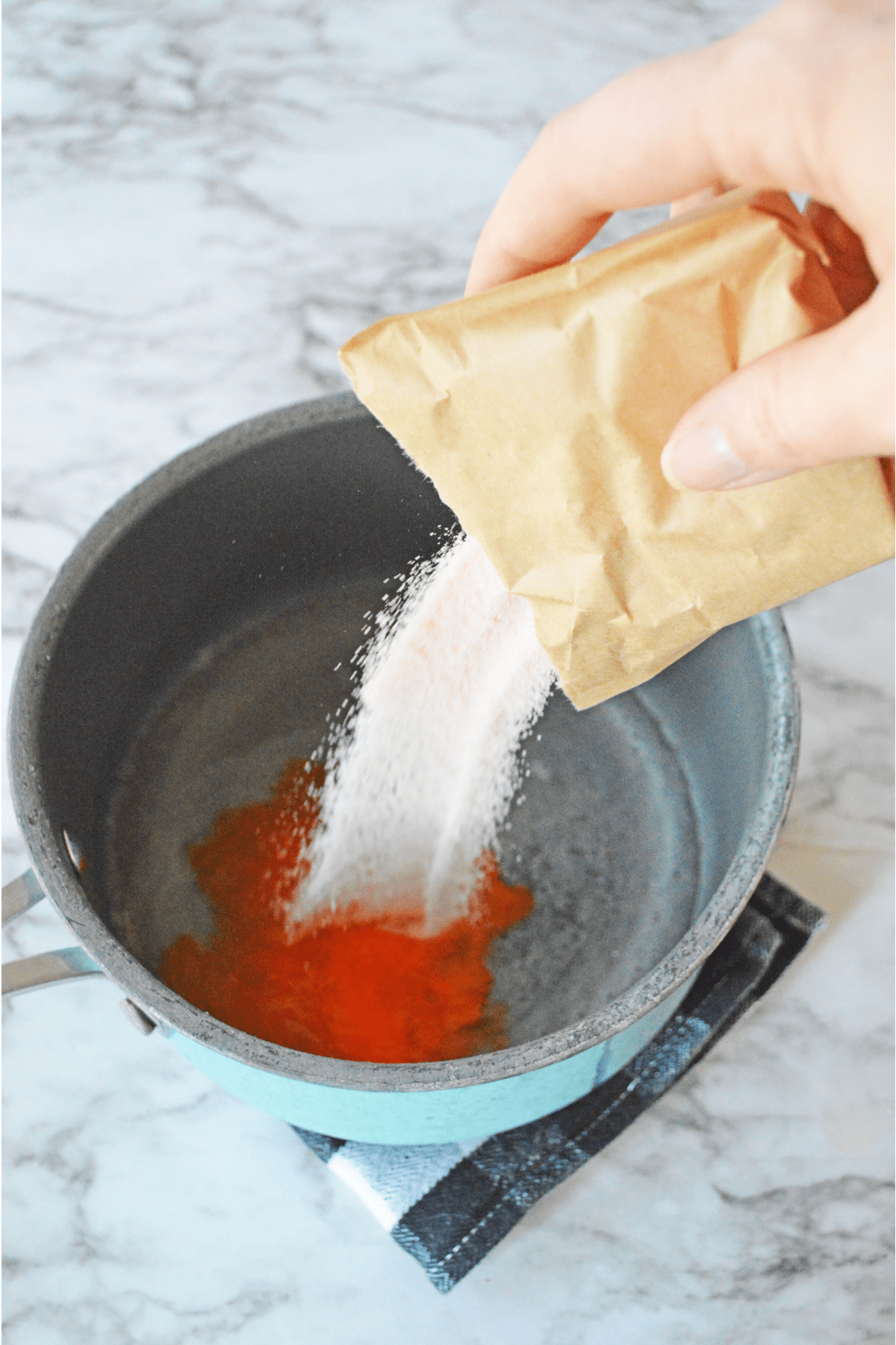 Orange jello poured into saucepan with water