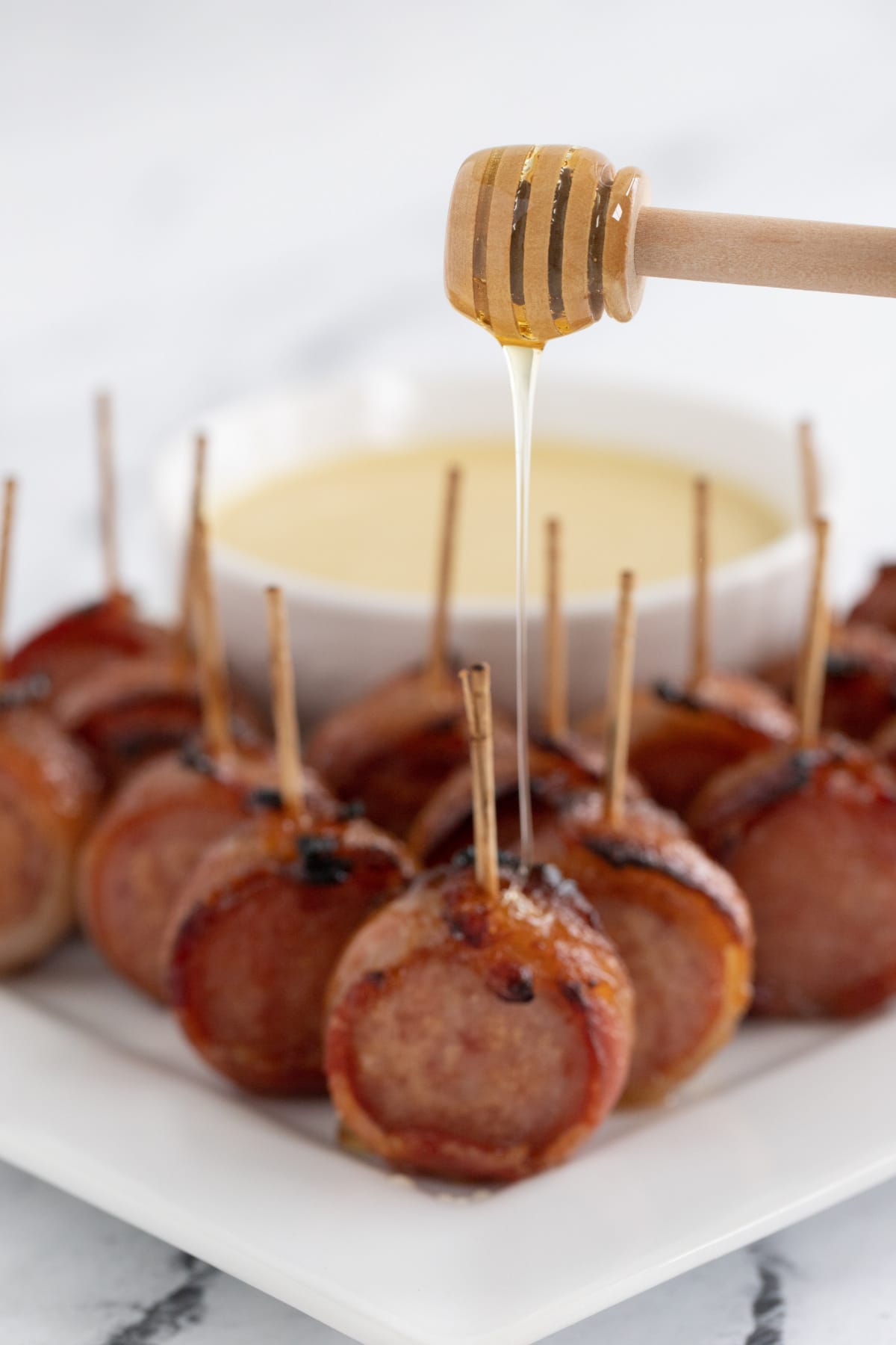 Drizzling honey over sausage appetizer